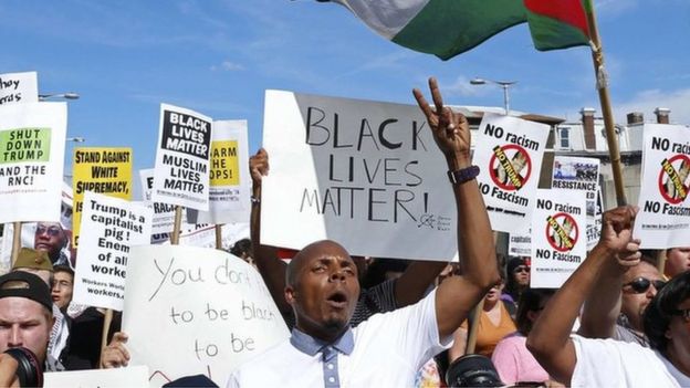 Demonstrators hold placards, including 