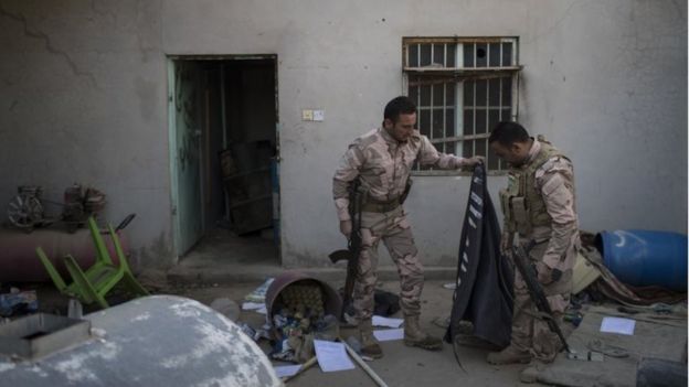 Combatientes kurdos peshmerga sostienen una bandera de Estado Islámico abandonada en una casa de Faziliya, al norte de Mosul, en Irak, el 2 de noviembre de 2016.