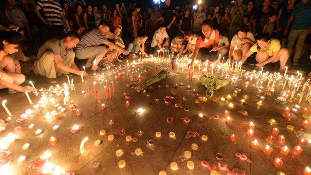 People lay candles on the ground as part of a vigil for the victims of the Kunshan blast