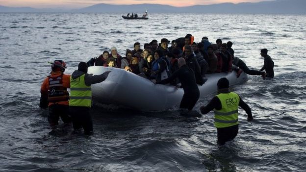 Volunteers and lifeguards help an inflatable boat with migrants after crossing the sea from Turkey to Lesbos, 12 March