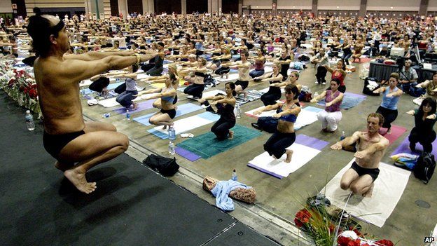 Bikram Choudhury doing yoga poses in a class of many people