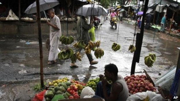 Locals use umbrellas while shopping for vegetables as it rains in Kolkata, India, Thursday, Aug. 8, 2013.