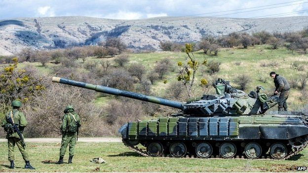 Russian soldiers stand near a tank outside a former Ukrainian military base in Crimea - 27 March 2014