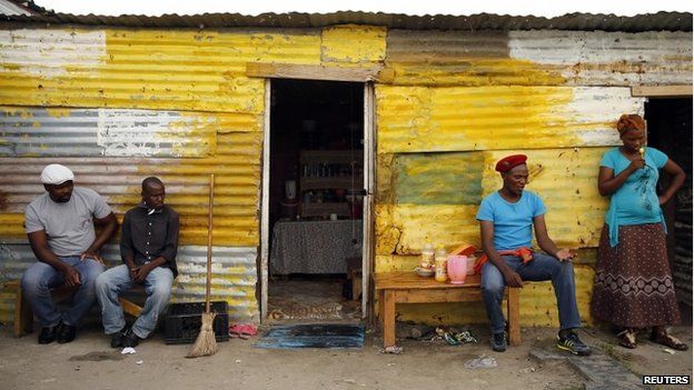 Members of a mining community sit outside their shacks in Nkaneng township in Rustenburg, South Africa, on 1 April 2014