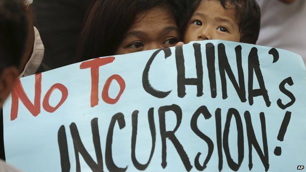 A Filipino protester holds a child as they join a rally outside the Chinese consulate at the financial district of Makati, south of Manila, Philippines on Tuesday, 22 April 2014
