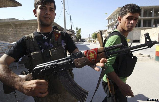 A Kurdish fighter from the Popular Protection Units (YPG) shows his weapon decorated with its flag in Aleppo, Syria (7 June 2014)