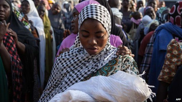 Women queue to receive humanitarian aid goods distributed by the Red Cross on 3 December 2014 in the Nigerian city of Yola after fleeing Boko Haram attacks