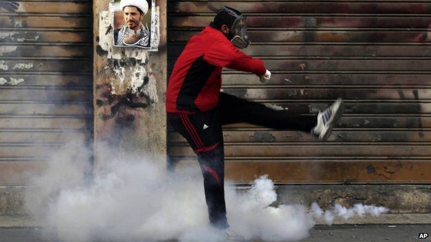 A Bahraini anti-government protester kicks away a tear gas canister fired by riot police (30 January 2015)