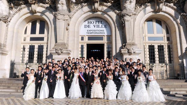 Chinese couples pose in front of the Tours city hall in October 2008