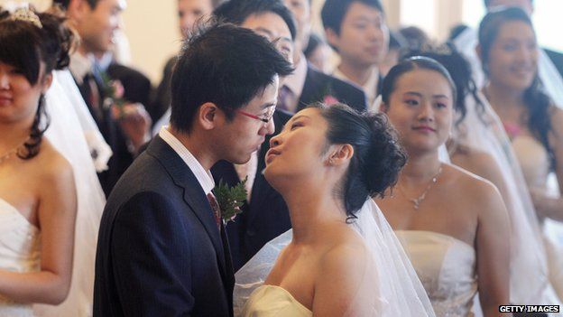 A newly-wed young Chinese couple kiss, as others look on, in front of the Tours city hall, in France Loire's Valley in October 2008