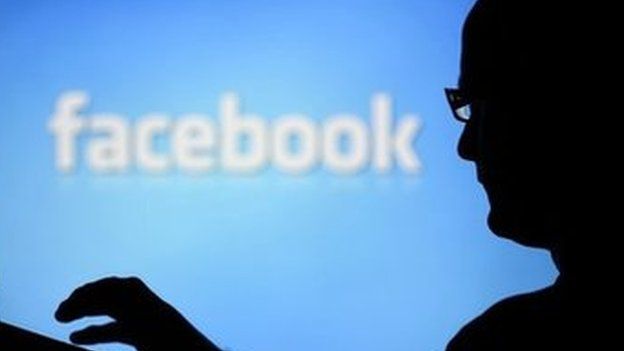 Um homem com um laptop é silhueta contra uma tela com um logotipo do Facebook em segundo plano 14 de agosto de 2013