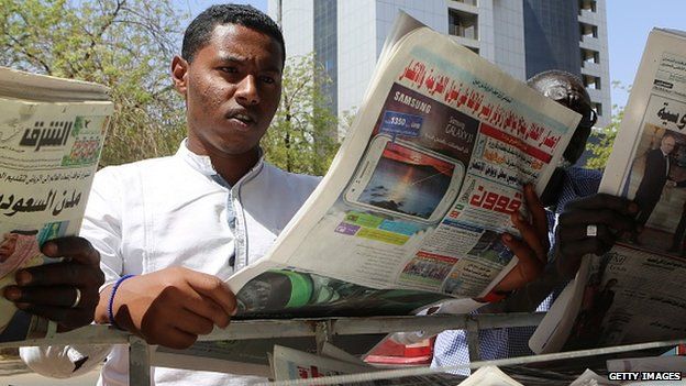 Sudanese men look at newspapers displayed at a kiosk in the capital Khartoum