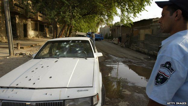 An Iraqi policeman stands by the bullet riddled car of two women allegedly shot dead by private security guards in central Baghdad, 9 October 2007.
