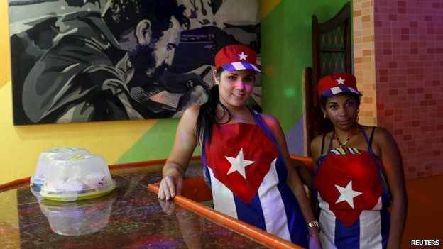 Waitresses at a Havana cafeteria, with a poster of Fidel Castro