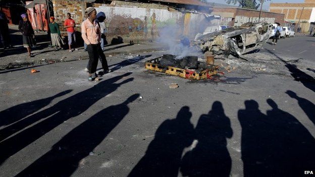 Smoke rises from a burning vehicle after another night of xenophobia related violence in Johannesburg, South Africa, 17 April 2015