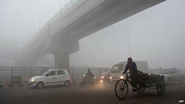 A rickshaw puller passes under a bridge early in Delhi