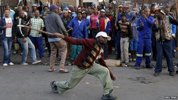 A local man gestures with a stick outside a hostel during the anti-immigrant violence in Johannesburg, April 17, 2015