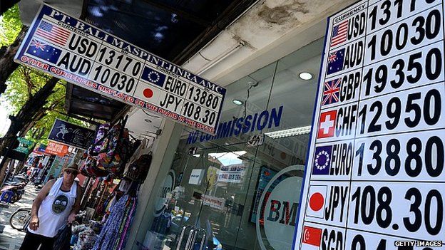 A tourist walks past a money changer on Bali on March 17, 2015