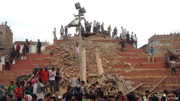 People stand around damage caused by an earthquake at Durbar Square in Kathmandu, Nepal, Saturday, April 25, 2015