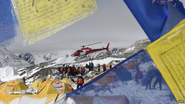 Prayer flags frame a rescue helicopter as it ferries injured people from Everest Base Camp - 26 April
