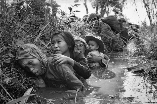 Women and children take cover from heavy fire about near Saigon, Vietnam 1 January 1966