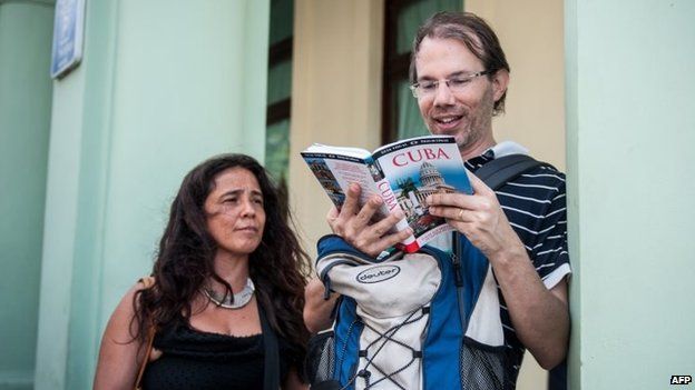 Tourists from the United States read a guide book on Cuba, in the streets of Havana on 6 April, 2015.