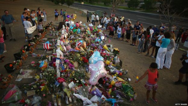 People visit a memorial set up near the cinema