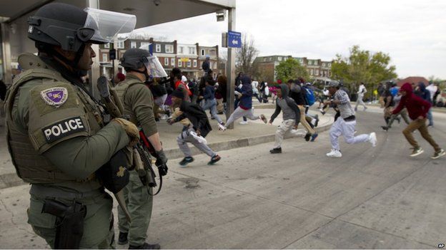 People running as police stand nearby