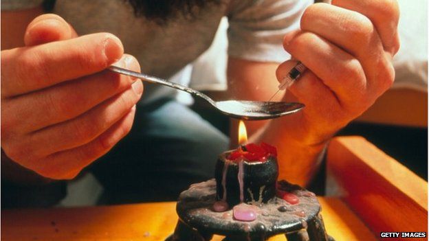 A man heats heroin in a spoon over a flame