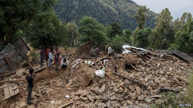 Villagers gather near a damaged house where three were killed by the earthquake at Jharibar Village, in Gorkha district close to the epicentre, on 28 April 2015