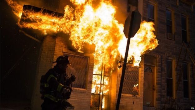 Police and firefighters respond in front of a building that caught fire as protests of the death of Freddie Gray continue in Baltimore, Maryland, USA, late 27 April 2015.