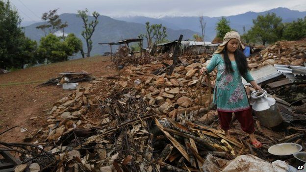 Uma mulher se recupera panelas de seu colapso casa destruída aldeia de Paslang em Gorkha