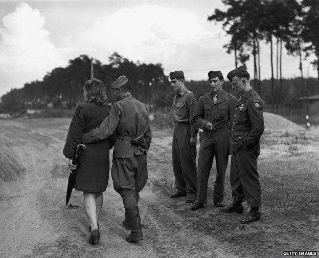 Circa 1945: GIs watch one of their Russian allies as he goes out walking with his girlfriend in Berlin