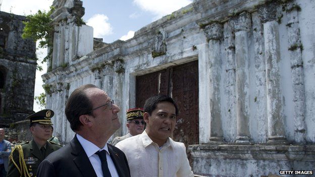 French President Francois Hollande (L) and Guiuan mayor Christopher Sheen (R) visit a church destroyed by a typhoon in 2013 in Guiuan on February 27, 2015. Hollande on February 27 visited a remote Philippine town devastated by one of the world's strongest typhoons, seeking to sound a global alarm on climate change ahead of a crucial UN summit