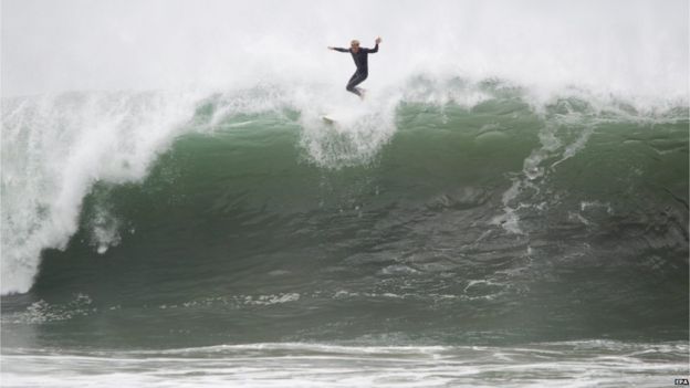 A man rides the rail of a wave