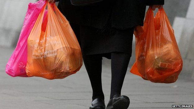 A woman carries several Sainsbury's bags of shopping