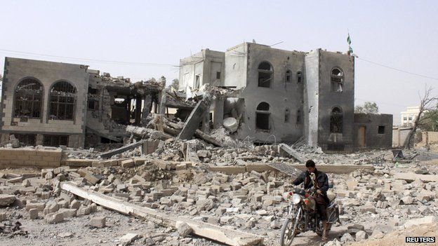 A man rides a motorcycle past a headquarters of the Houthi group, which was destroyed after an air strike by a Saudi-led coalition, in Saada, Yemen (April 26, 2015)