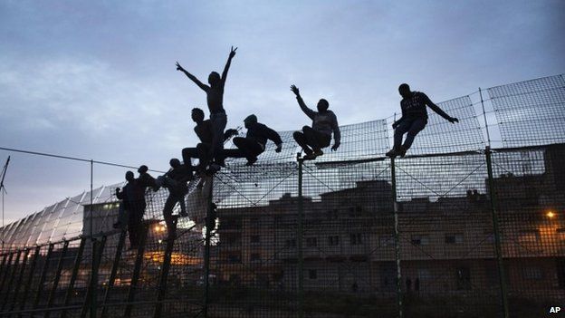 Sub-Saharan migrants climb over a metallic fence that divides Morocco and the Spanish enclave of Melilla. March 28, 2014