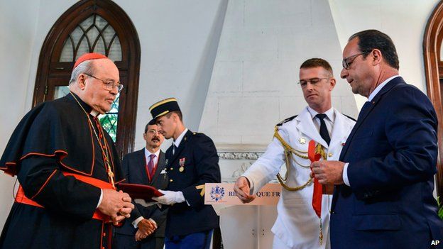 French President Francois Hollande, right, honors Cuban Cardinal Jaime Ortega with the Order Commander of the Legion of Honor at the French Embassy in Havana, Cuba, Monday, May 11, 2015.