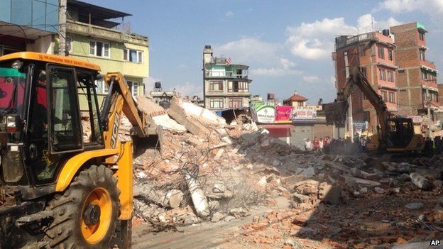 Earthmovers remove debris from a building that collapsed in an earthquake in Kathmandu, Nepal, Tuesday, May 12, 2015.