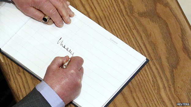 Prince Charles signs a visitor's book in Belfast