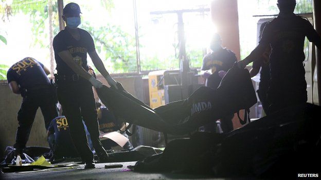Members of the Scene of the Crimes Operatives bring in bags of charred bodies of the workers at municipal hall in Valenzuela city, north of Manila on 14 May 2015.