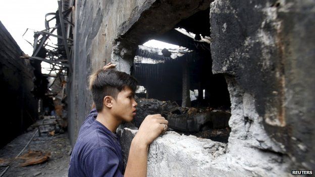 A worker who survived the fire look inside a gutted footwear factory in Valenzuela, Metro Manila in the Philippines on 14 May 2015. The
