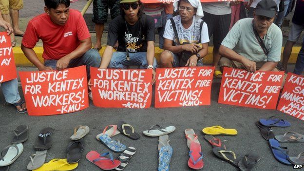Protesters hold placards, while displaying sandals on the ground, during a rally to call for justice for the victims of a fire that gutted a footwear factory the day before, in Manila on 14 May 2015.