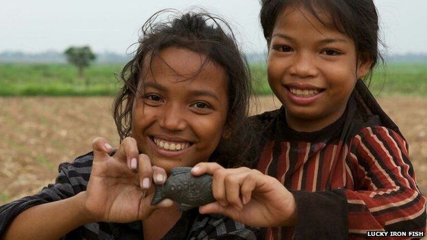 Children holding an iron fish in Cambodia