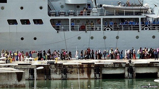 Rohingya women migrants and children stand in a queue to board a Malaysian Navy ship at the naval base in Langkawi on May 14, 2015 to be transferred to a mainland immigration depot.