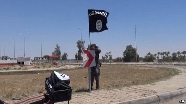 An image grab taken from a video uploaded on 18 May 2015 by Aamaq News Agency, a YouTube channel which posts videos from areas under the Islamic State (IS) group's control, allegedly shows an IS fighter hanging a flag of the group in a street of Ramadi, the Iraqi capital of Anbar province, a day after the city was captured by IS