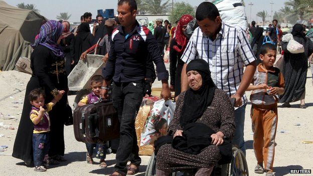A displaced Iraqi Sunni man pushes an elderly woman in a wheelchair on the outskirts of Baghdad, on 17 May 2015