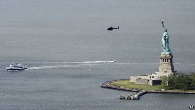A ferry and helicopter pass the Statue of Liberty in this view from the observatory at One World Trade Center, Wednesday, May 20, 2015, in New York