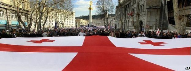 Georgians carry a giant national flag during an opposition rally in Tbilisi